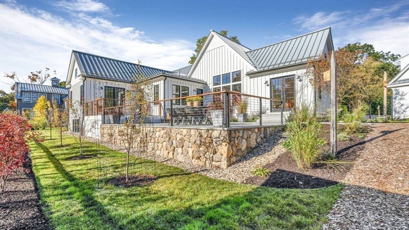 The same property completed, with a fieldstone retaining wall, new lawn, gravel paths and young planting.